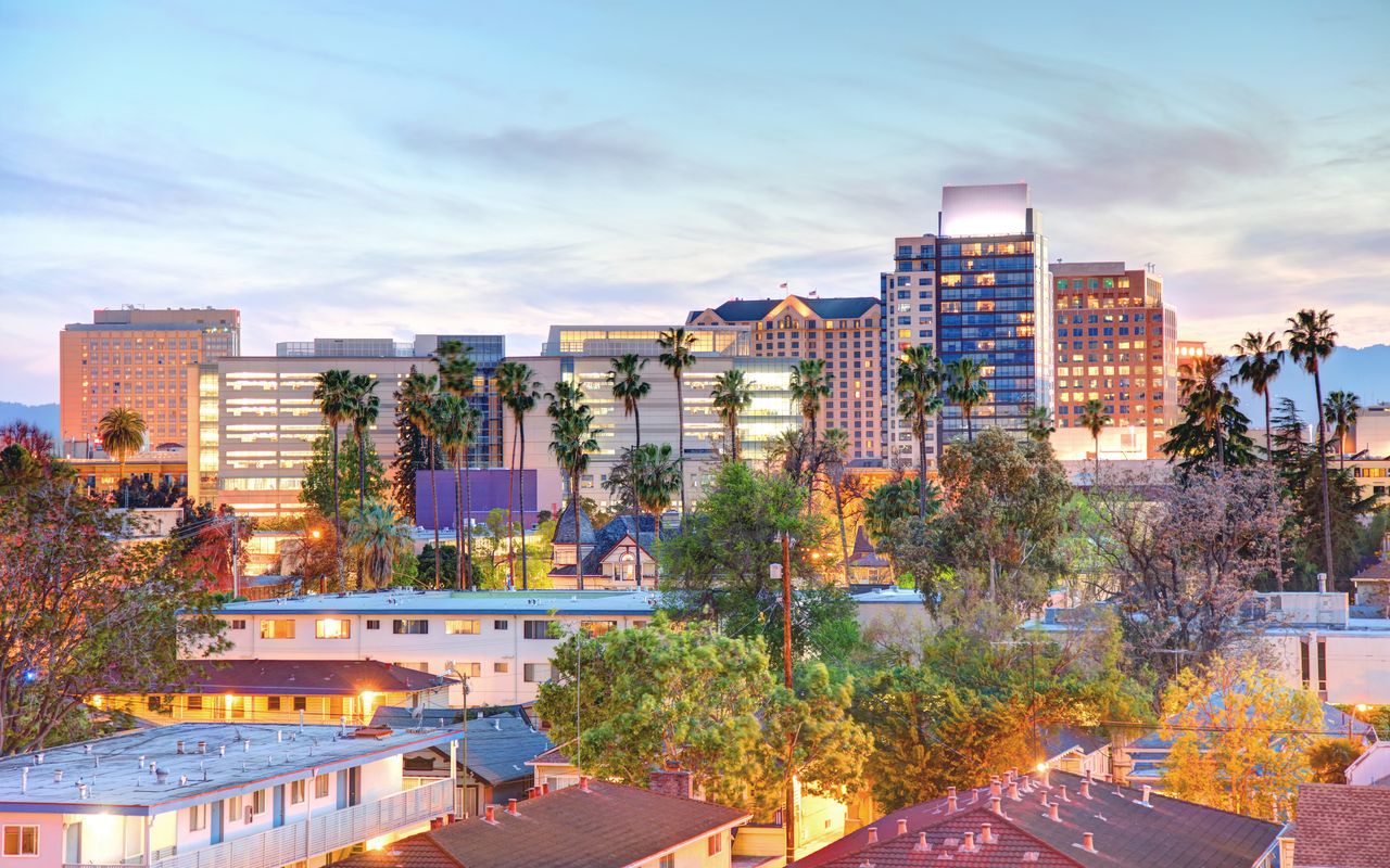Downtown San Jose towers and palm trees at dusk, above the rooftops of nearby neighborhoods